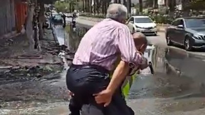 Hatay'da bir trafik polisi depremzedeyi su basan caddeden sırtında taşıyarak geçirdi